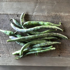 A group of fresh green beans on a wooden surface.
