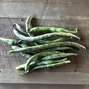 A group of fresh green beans on a wooden surface.