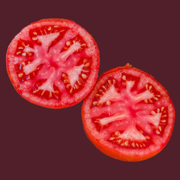 Two slices of red tomato, showing the inner flesh and seeds against a purple background.