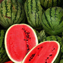 A pile of whole watermelons with a couple of slices showing the red flesh and black seeds.