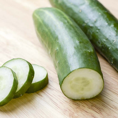 A photo showing fresh whole cucumbers and sliced cucumbers on a wooden surface.