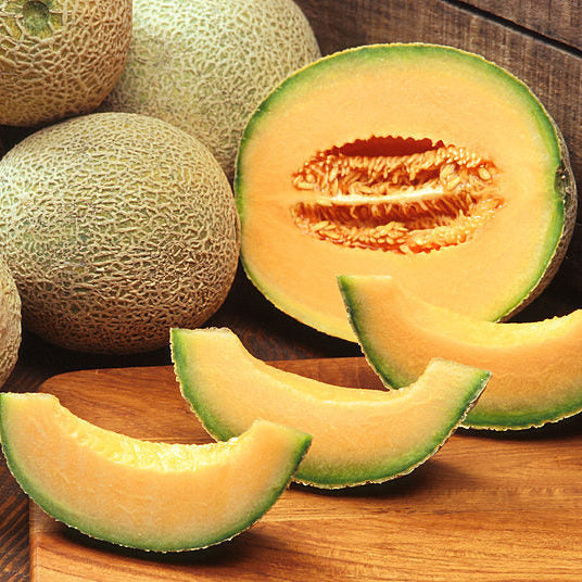 Melons, including a sliced cantaloupe, on a wooden surface