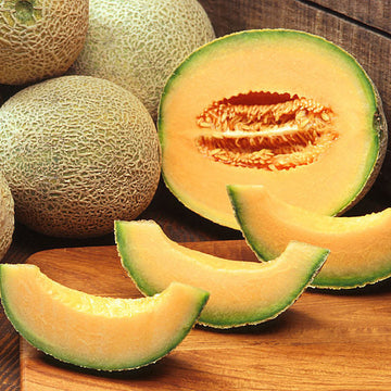 Melons, including a sliced cantaloupe, on a wooden surface