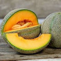 Two cantaloupes, one sliced open, on a wooden surface.