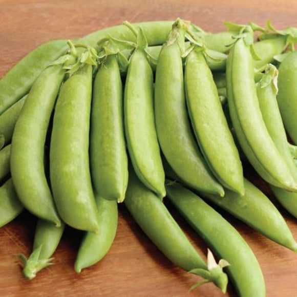 A cluster of fresh green pea pods laid out on a wooden surface.