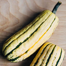 Two striped squash on a wooden surface